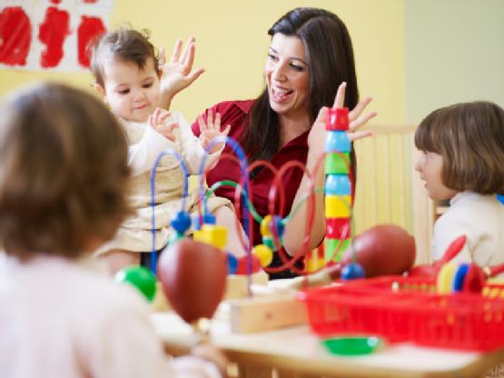 three little girls and female teacher in kindergarten