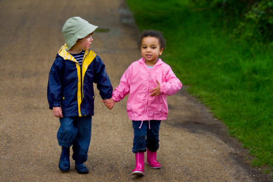 Two Children Holding Hands Walking Through A Park