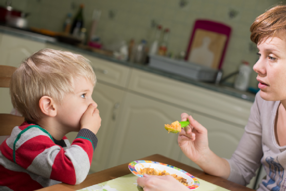 Young boy holds hand on his mouth to stop eating