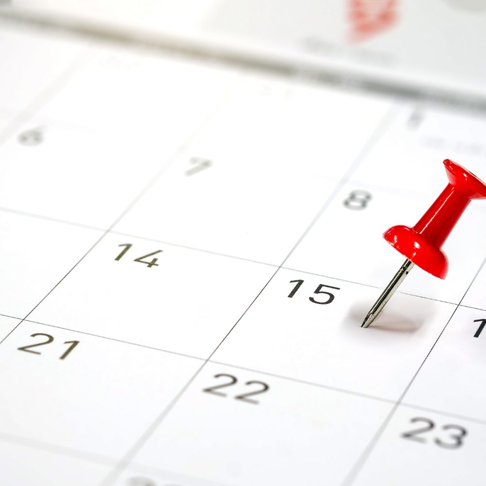 Embroidered red pins on a calendar on the 15th with selective focus